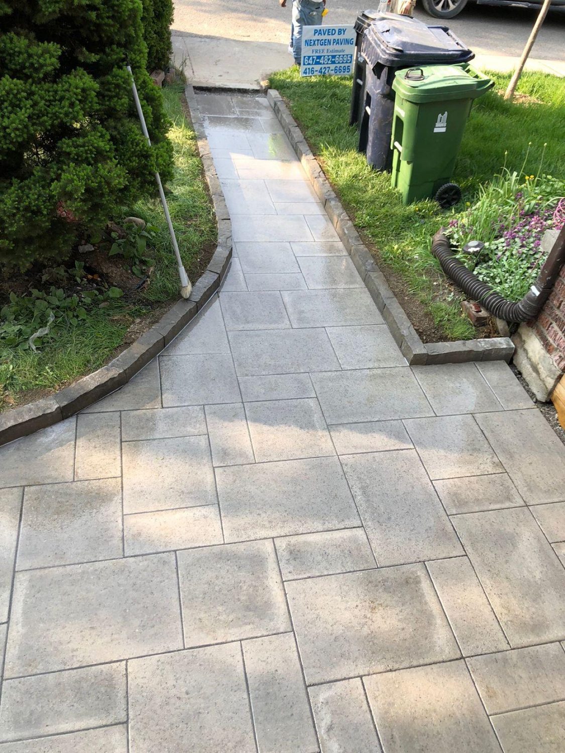 Finished interlock walkway by Next Gen Paving with a Paved By NextGen sign